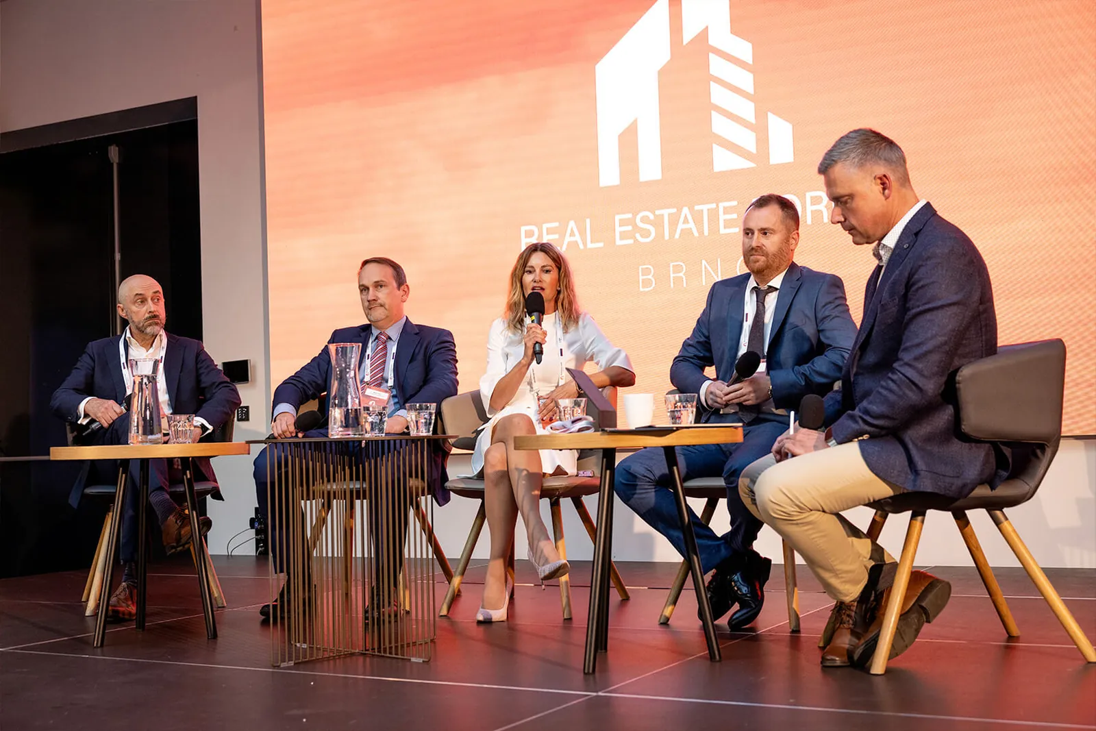 Diskusní panel o investicích do nemovitostí — pět panelistů na pódiu